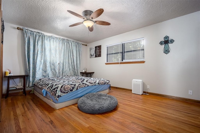 bedroom featuring hardwood / wood-style flooring, ceiling fan, and a textured ceiling