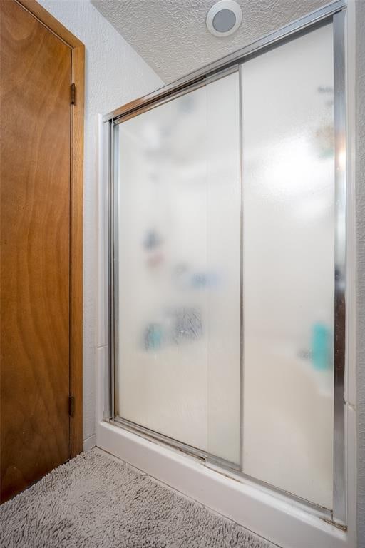 bathroom featuring a shower with door and a textured ceiling