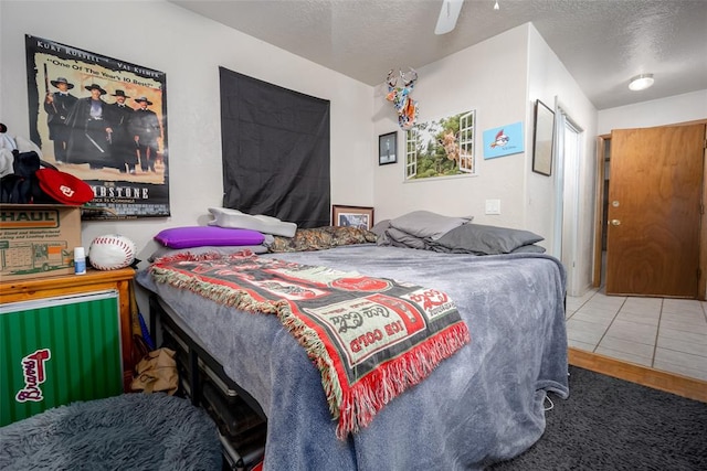 tiled bedroom with ceiling fan and a textured ceiling