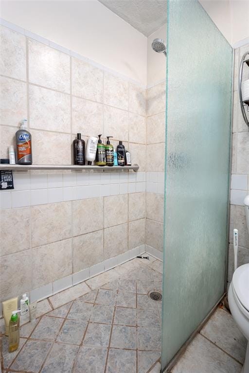 bathroom featuring tile patterned flooring, toilet, and a shower with door