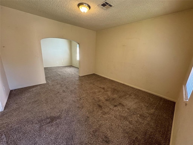 spare room with dark carpet and a textured ceiling