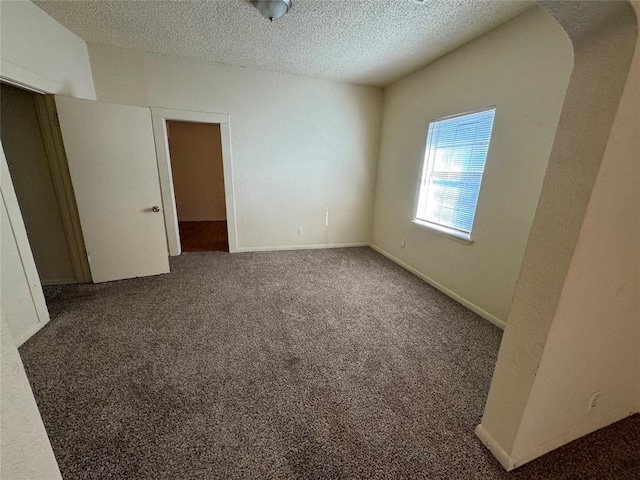 empty room featuring dark colored carpet and a textured ceiling