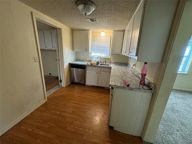 kitchen with hardwood / wood-style flooring, dishwasher, plenty of natural light, and white cabinetry