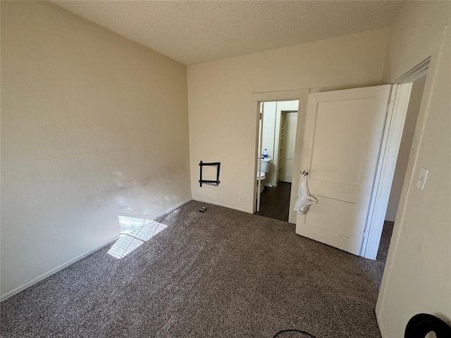 spare room with a textured ceiling and dark carpet