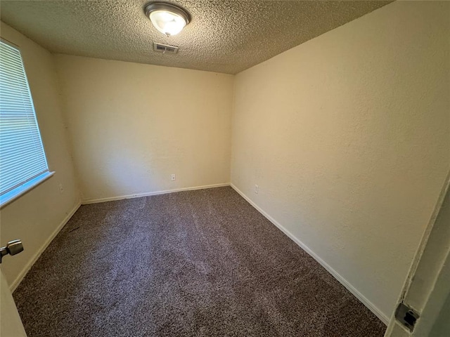 carpeted empty room with a textured ceiling