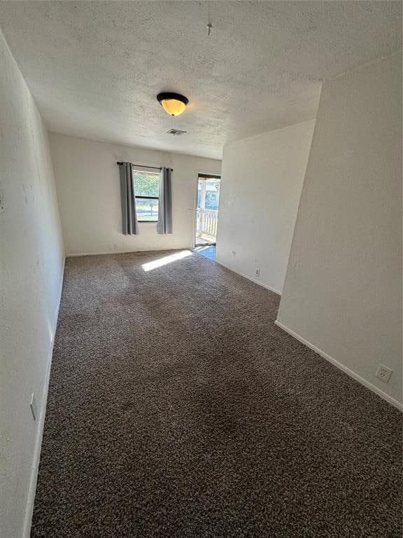 empty room with carpet flooring and a textured ceiling