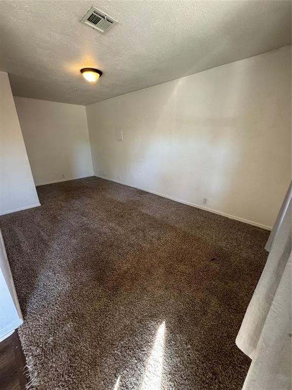 unfurnished room featuring dark carpet and a textured ceiling