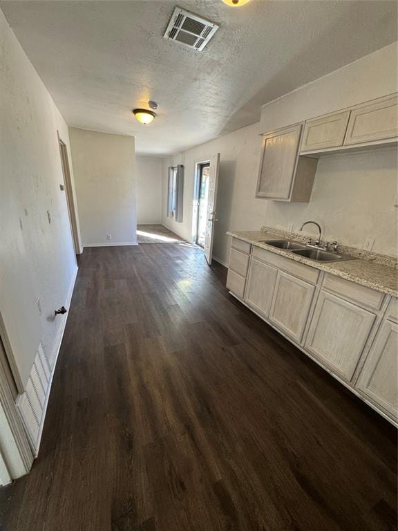 kitchen with a textured ceiling, dark wood-type flooring, and sink