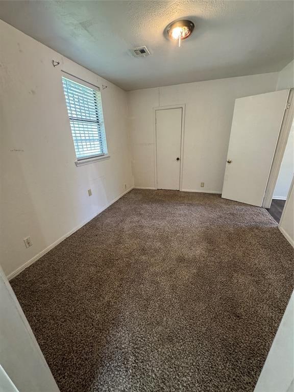 empty room featuring carpet and a textured ceiling