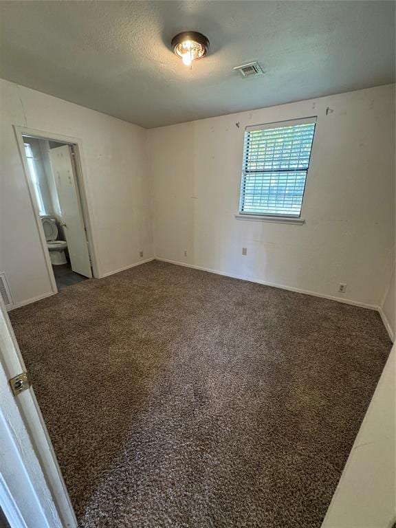 spare room with a textured ceiling and dark carpet