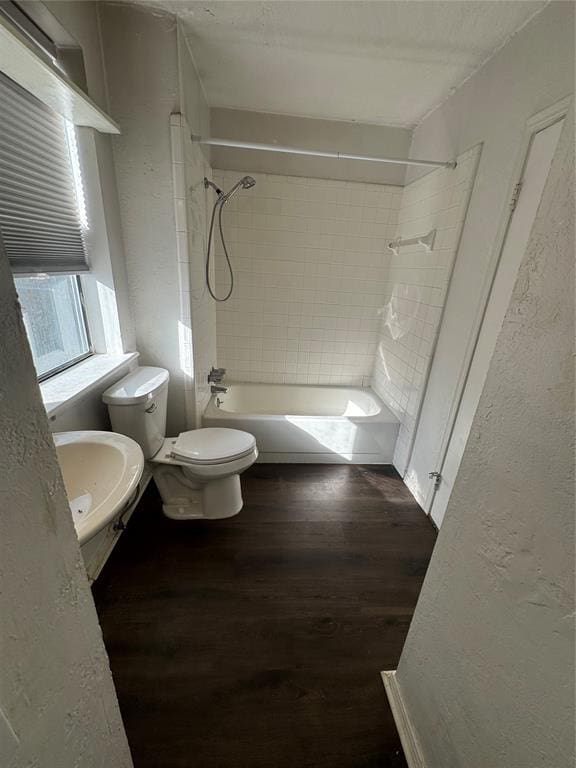 full bathroom with hardwood / wood-style floors, tiled shower / bath combo, toilet, and sink