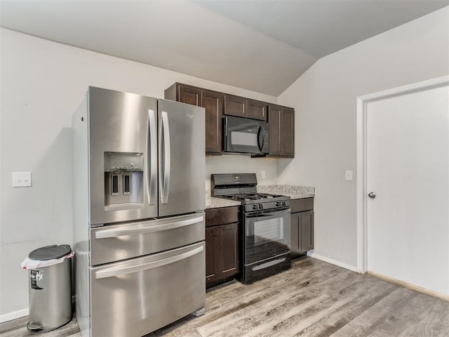 kitchen featuring dark brown cabinets, black appliances, vaulted ceiling, and light hardwood / wood-style floors