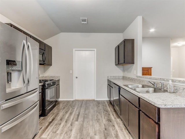 kitchen featuring appliances with stainless steel finishes, light wood-type flooring, dark brown cabinets, sink, and lofted ceiling