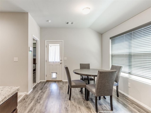 dining area with vaulted ceiling and light hardwood / wood-style flooring