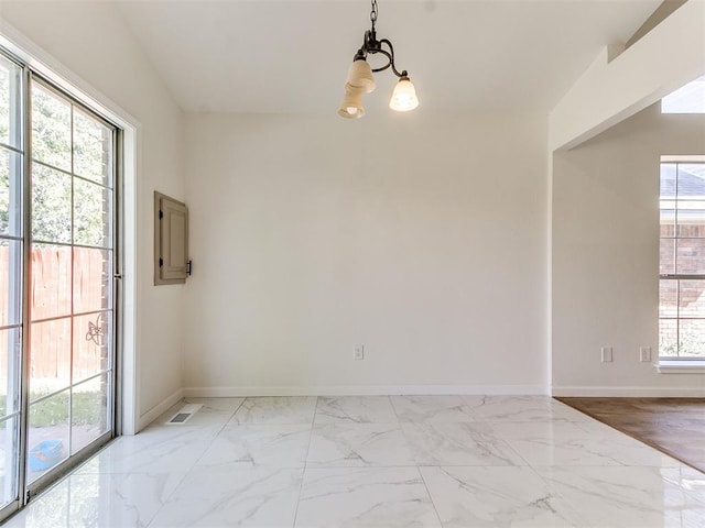 spare room featuring light hardwood / wood-style flooring, a wealth of natural light, and a notable chandelier