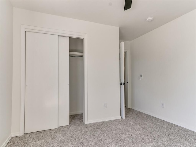 unfurnished bedroom with ceiling fan, light carpet, and a closet