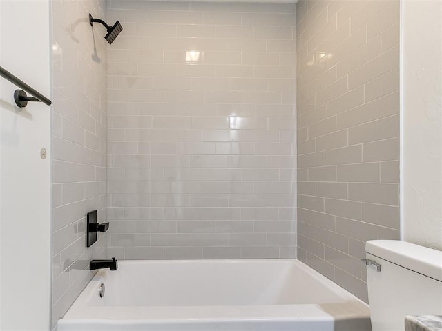 bathroom featuring toilet and tiled shower / bath