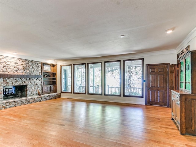 unfurnished living room with crown molding, a fireplace, light hardwood / wood-style floors, and a textured ceiling