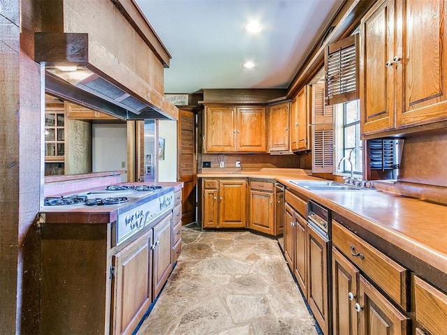 kitchen featuring stainless steel gas stovetop, custom exhaust hood, paneled dishwasher, and sink