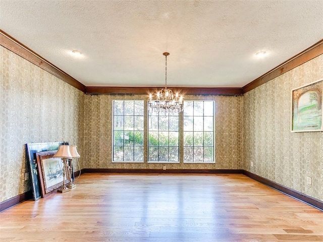 unfurnished dining area featuring wood-type flooring, a textured ceiling, and crown molding