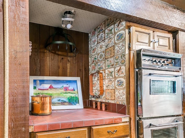 kitchen featuring tile countertops and wooden walls