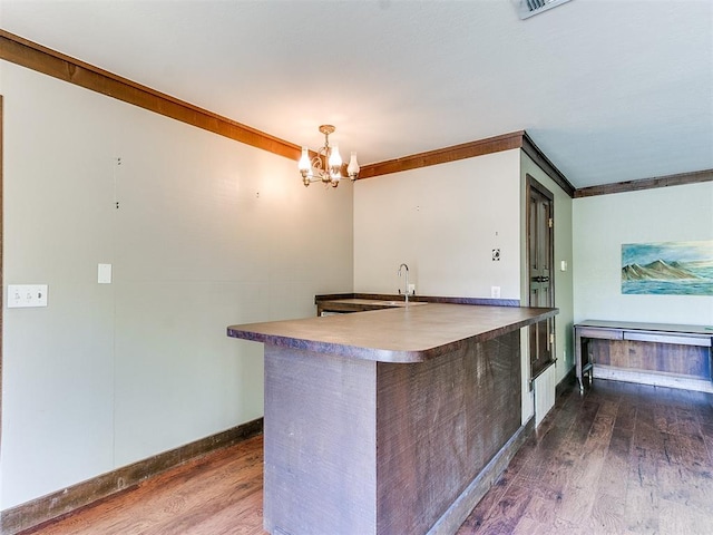 kitchen featuring a chandelier, dark hardwood / wood-style floors, hanging light fixtures, and ornamental molding