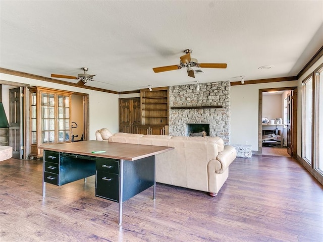 living room featuring a fireplace, wood-type flooring, ceiling fan, and crown molding