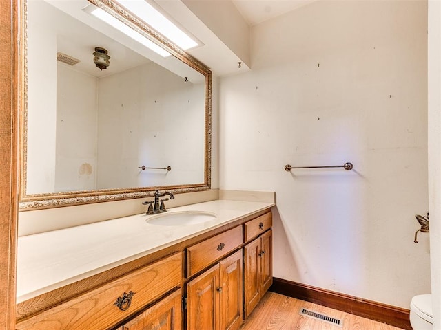 bathroom featuring wood-type flooring, vanity, and toilet