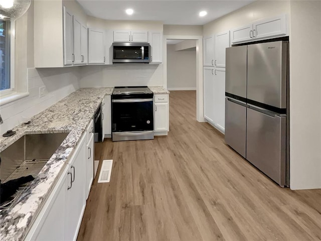 kitchen with white cabinetry, light hardwood / wood-style flooring, light stone countertops, and appliances with stainless steel finishes