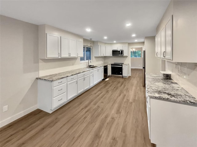 kitchen with light stone counters, stainless steel appliances, sink, light hardwood / wood-style flooring, and white cabinets