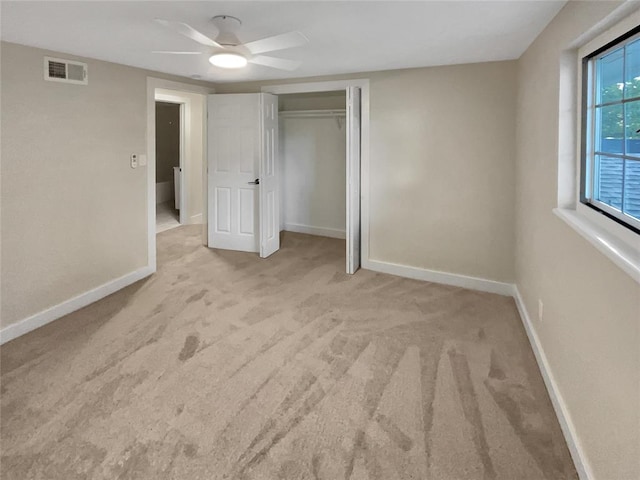 unfurnished bedroom with ceiling fan, light carpet, and a closet