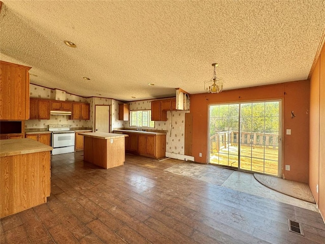 kitchen featuring electric range, dark wood-type flooring, pendant lighting, a textured ceiling, and a kitchen island