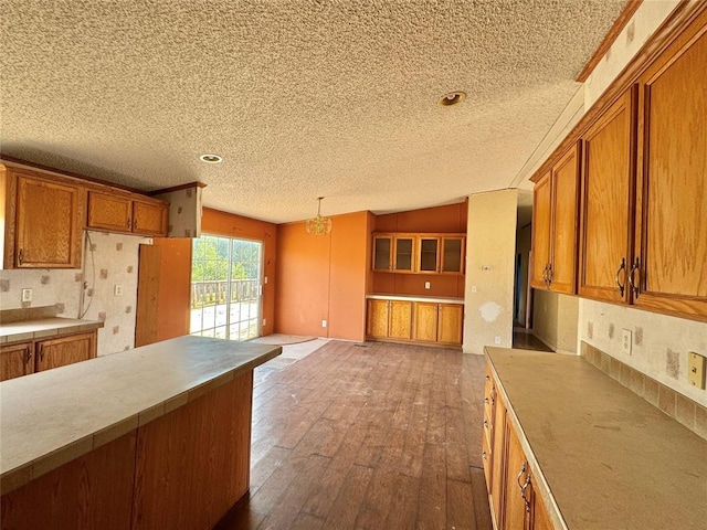 kitchen with a textured ceiling, dark hardwood / wood-style flooring, vaulted ceiling, and hanging light fixtures