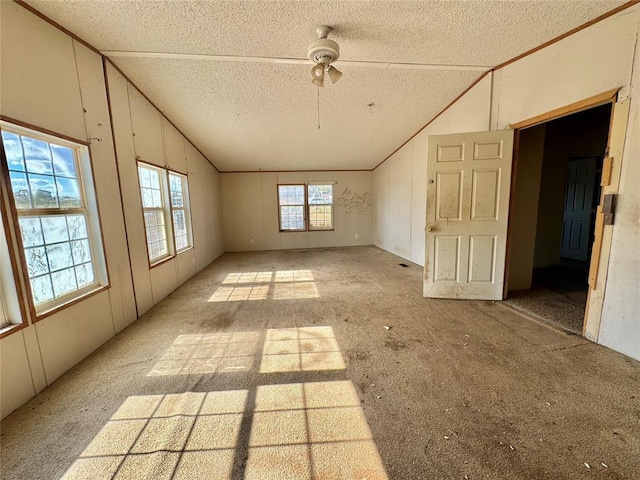 empty room with a textured ceiling, vaulted ceiling, and ceiling fan