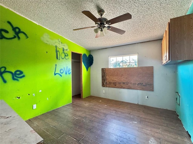 empty room with dark hardwood / wood-style floors, ceiling fan, and a textured ceiling