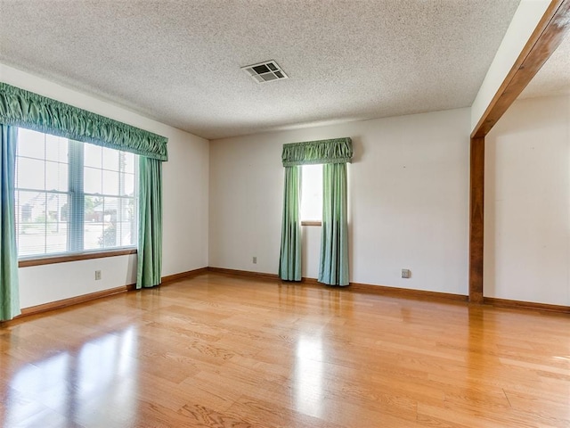 spare room featuring light wood-type flooring and a textured ceiling