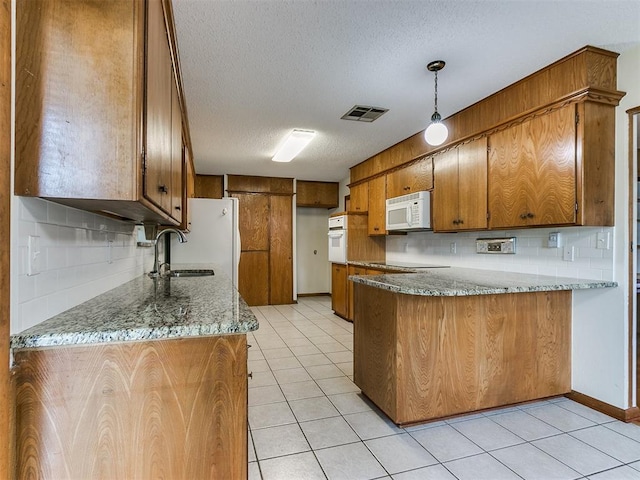 kitchen with pendant lighting, white appliances, backsplash, light tile patterned flooring, and light stone counters