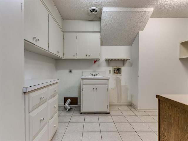 laundry room featuring cabinets, hookup for an electric dryer, hookup for a washing machine, a textured ceiling, and light tile patterned floors