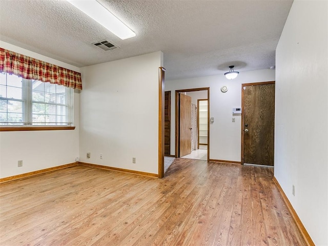 empty room featuring a textured ceiling and light wood-type flooring