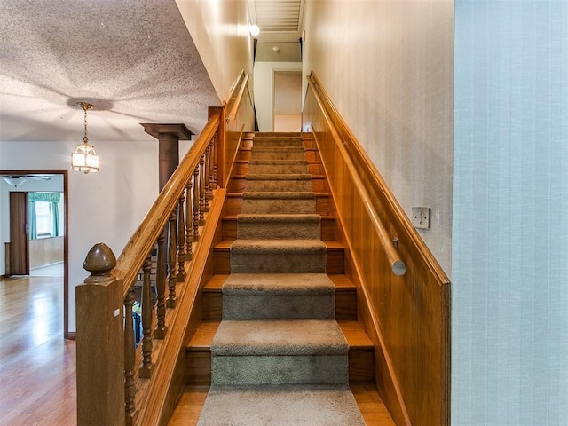 staircase with hardwood / wood-style flooring and an inviting chandelier