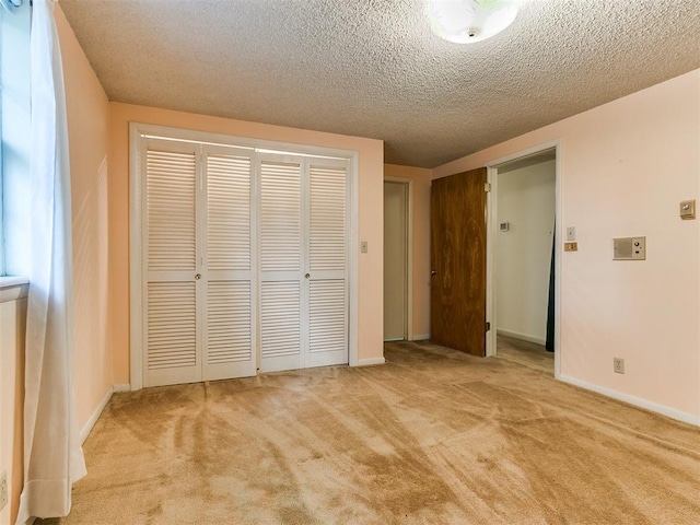 unfurnished bedroom featuring a closet, light colored carpet, and a textured ceiling