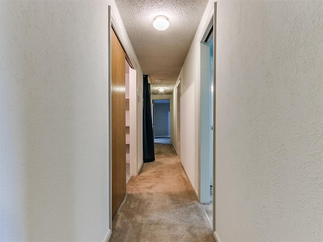 hallway featuring a textured ceiling and light carpet