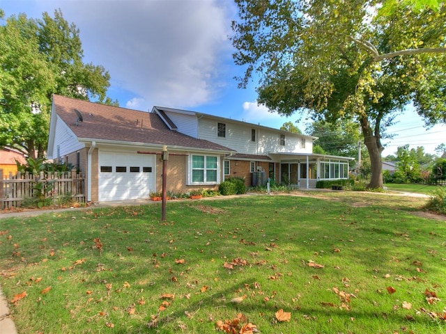 view of property with a garage, a front lawn, and a sunroom