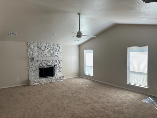 unfurnished living room featuring ceiling fan, a stone fireplace, a wealth of natural light, and vaulted ceiling