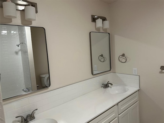 bathroom featuring a tile shower, vanity, and toilet