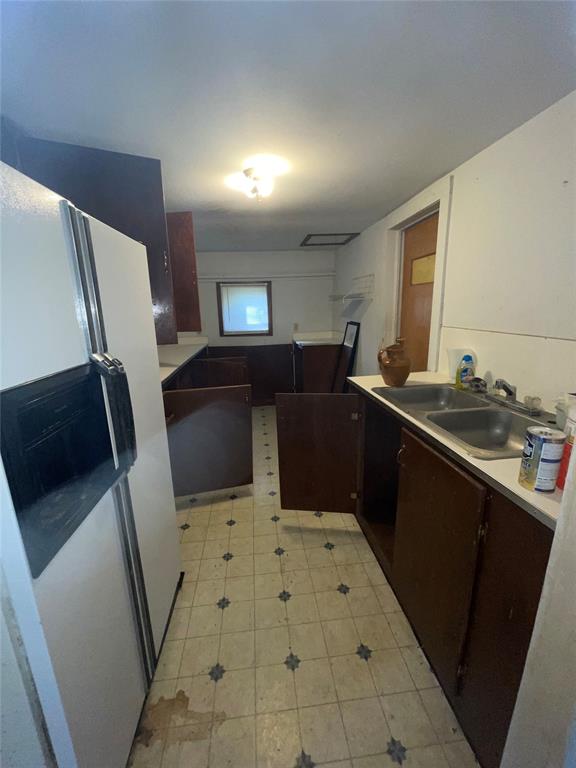 kitchen featuring white refrigerator, dark brown cabinetry, and sink