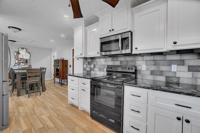 kitchen featuring dark stone counters, light wood-type flooring, appliances with stainless steel finishes, tasteful backsplash, and white cabinetry