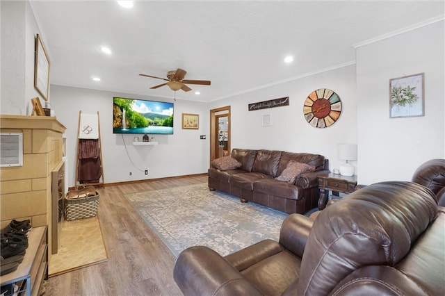 living room featuring ceiling fan, a fireplace, wood-type flooring, and ornamental molding