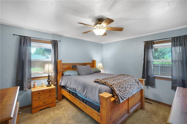 bedroom featuring ceiling fan, light carpet, and multiple windows