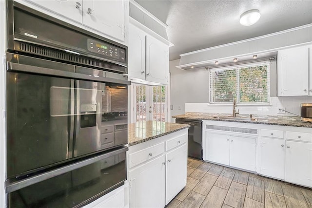 kitchen featuring black appliances, a healthy amount of sunlight, white cabinets, and dark stone countertops